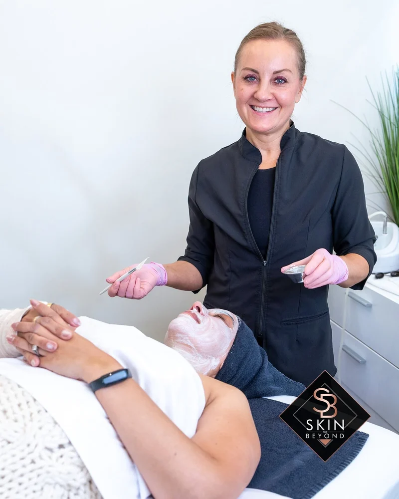 Esthetician applying a facial mask during treatment at Skin and Beyond Spa